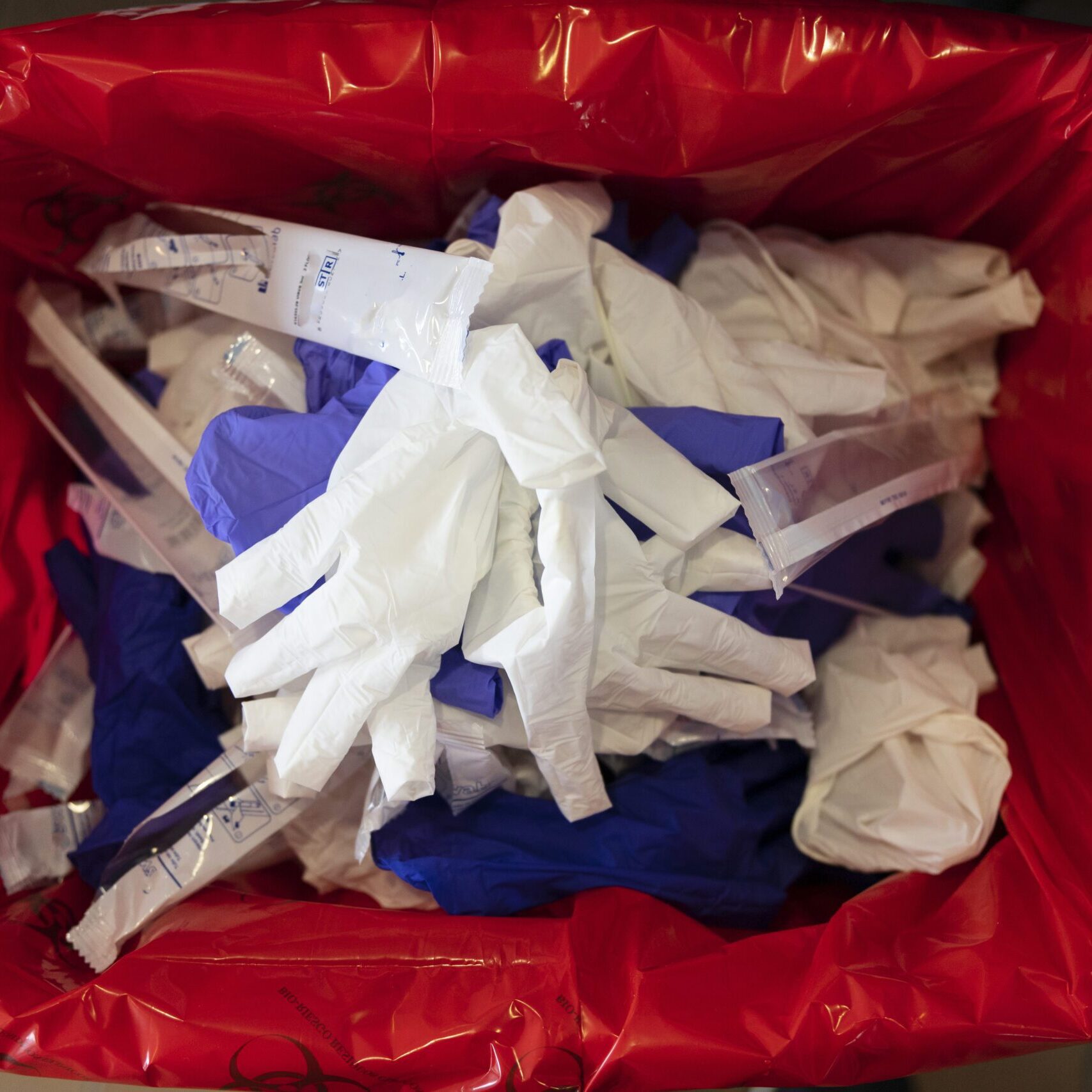 Medical waste disposal like gloves from a healthcare facility in a red bag.